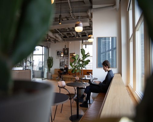 Person working on laptop in a bright coworking space avoiding direct window glare