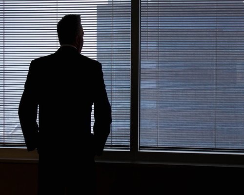 Person looking out of a window from an office taking a short break