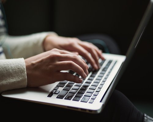 Close up of hands adjusting laptop screen brightness